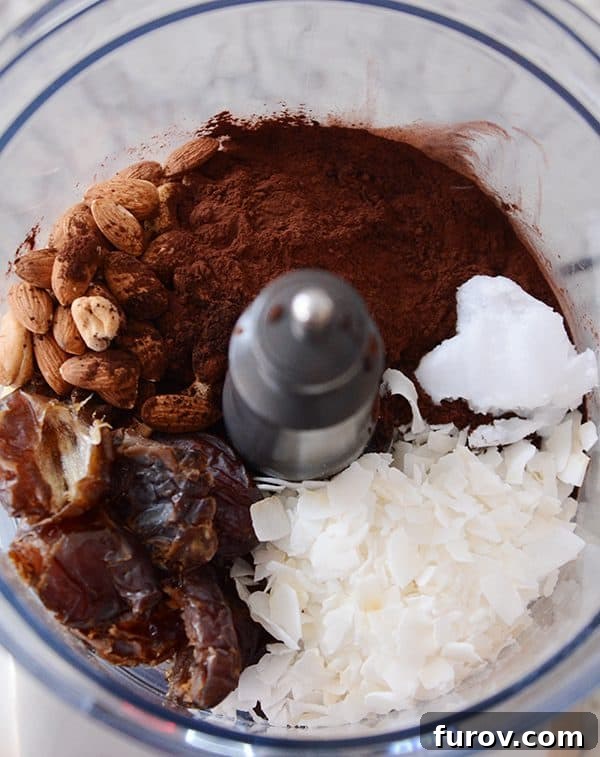 A food processor full of ingredients to make dark chocolate almond joy bites. 