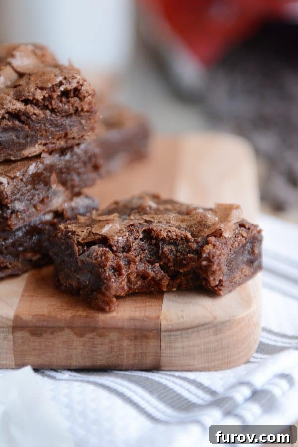 A stack of brownies with one in front with a bite taken out. 