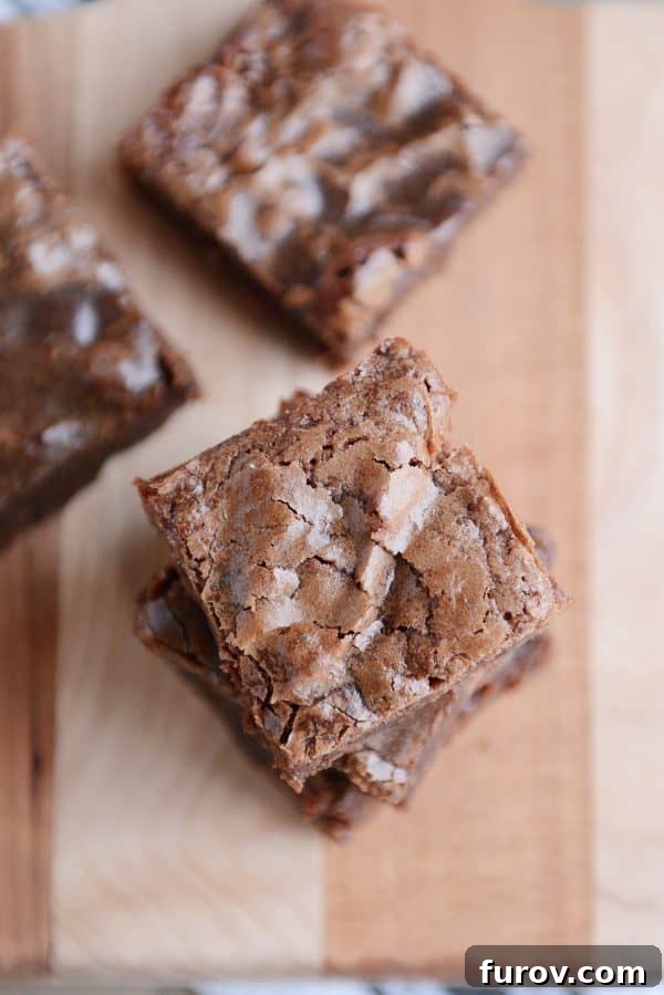 A stack of chocolate brownies on a wooden cutting board. 