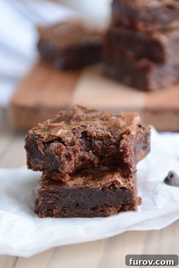 A stack of brownies with a bite taken out of the top one. 