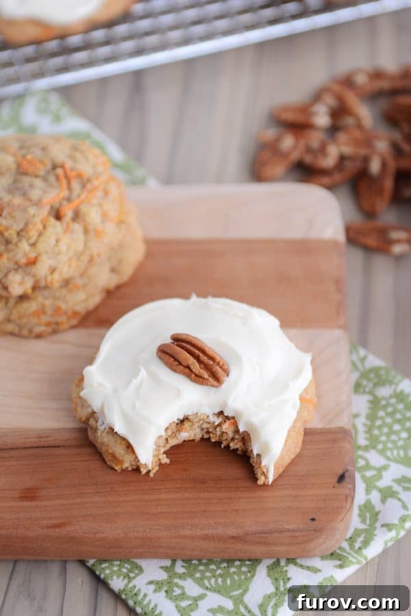 Heavenly Carrot Cake Cookies with Tangy Cream Cheese Frosting 5 A frosted carrot cake cookie with a significant bite taken out, revealing its texture.