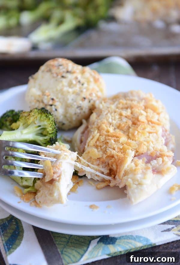 One-Pan Cordon Bleu Chicken & Broccoli Roast 2 A perfectly cooked piece of unstuffed sheet pan chicken cordon bleu, golden brown and cheesy, served on a white plate with tender roasted broccoli.