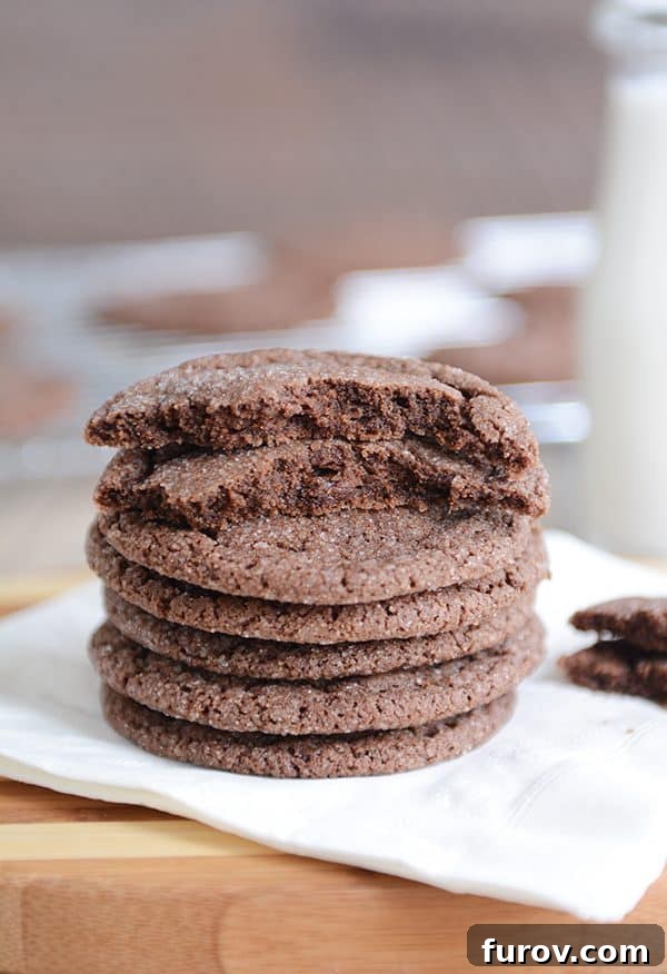 Stack of incredibly soft chocolate sugar cookies on a white napkin, with one cookie broken in half revealing its fudgy interior.