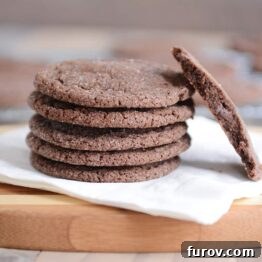Stack of chocolate sugar cookies on a white napkin with one in half.