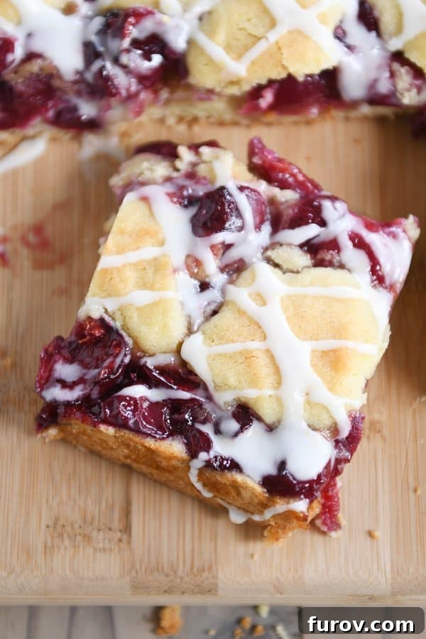 Cherry pie cookie bar on wood cutting board, showcasing its delightful texture and rich color.