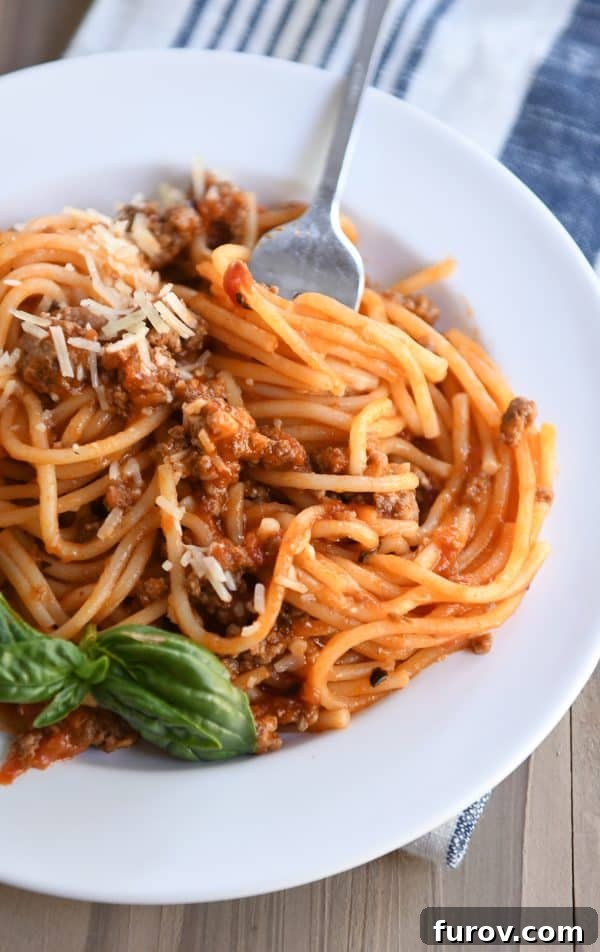 Instant Pot spaghetti twisted around a fork, resting on a white plate.