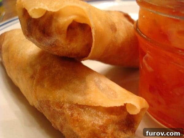 Marys Signature Egg Rolls 10 Two freshly fried, perfectly golden-brown egg rolls presented on a pristine white plate, showcasing their irresistible crispiness.