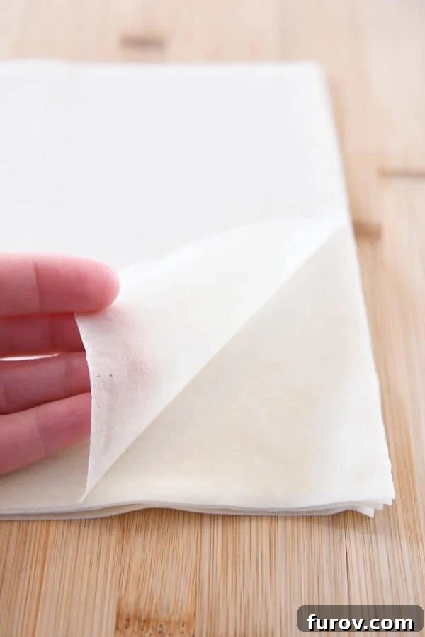 Marys Signature Egg Rolls 4 A stack of square, frozen spring roll pastry wrappers, essential for making light and crispy authentic egg rolls, awaiting defrosting.