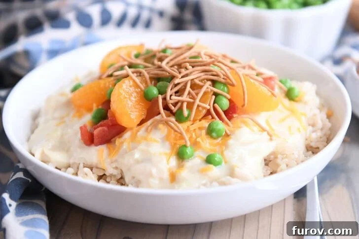 White bowl with brown rice, Hawaiian Haystacks gravy, mandarin oranges, chow mein noodles and peas, ready to be customized.