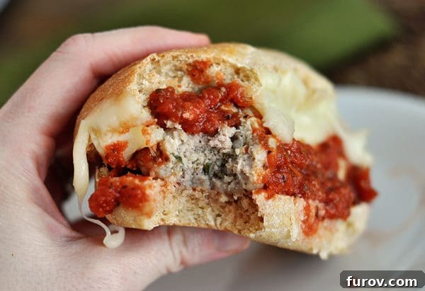bite taken out of an italian meatball and cheese sub sandwich, showing the juicy meatballs and melted mozzarella.