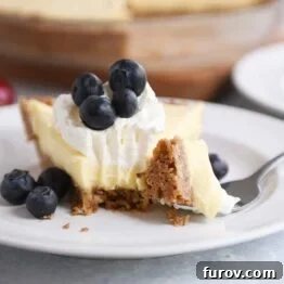 Berries and cream pie on a white plate with a bite taken out.