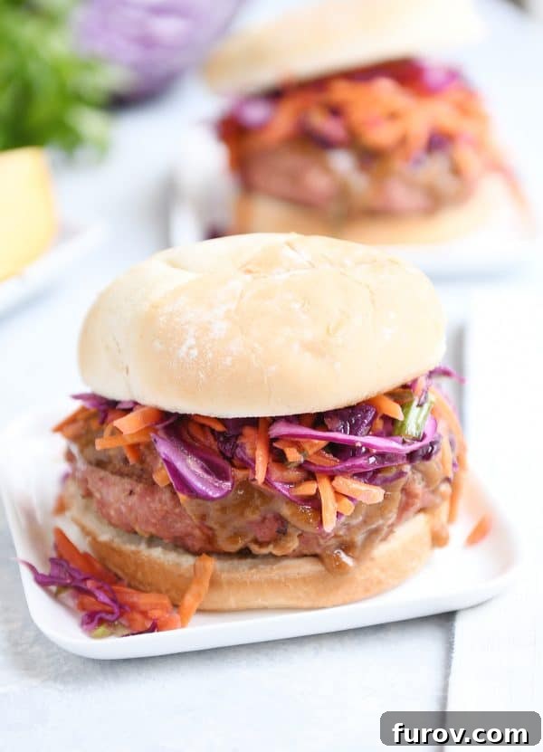 Thai burger with peanut sauce and tangy slow on white square plate.