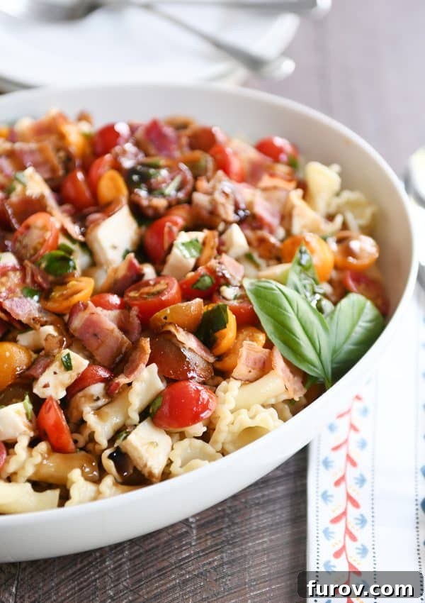 Ultimate Bruschetta Chicken Bacon Pasta 3 Bruschetta chicken and bacon pasta in large white serving bowl with fresh basil.
