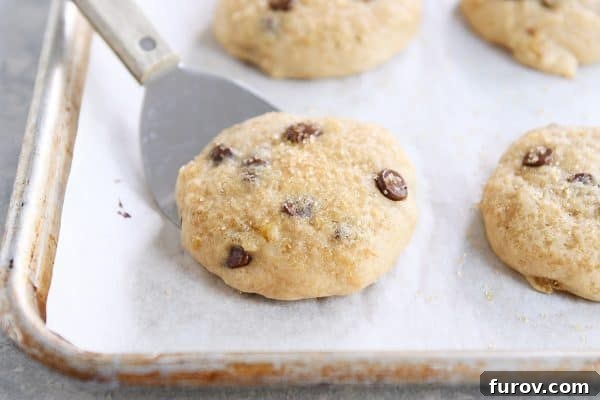 Pillowy Banana Bread Cookies 3 A single soft banana bread cookie resting on a baking pan with a spatula, highlighting its delicate texture.