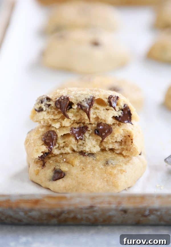 Pillowy Banana Bread Cookies 4 A soft banana bread cookie, broken in half on a baking sheet, revealing its moist interior.