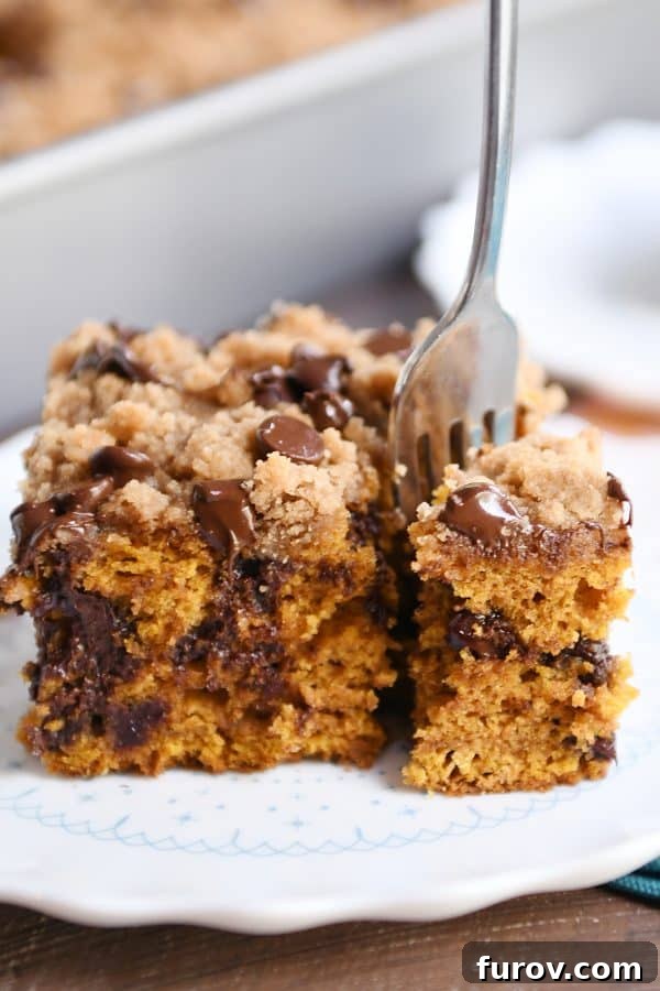 A fork digging into a slice of pumpkin chocolate chip streusel cake, highlighting its soft interior.