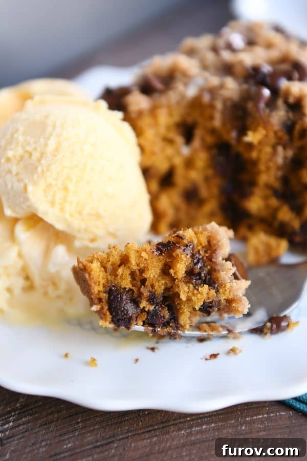 A slice of pumpkin chocolate chip streusel cake topped with a scoop of melting vanilla ice cream.