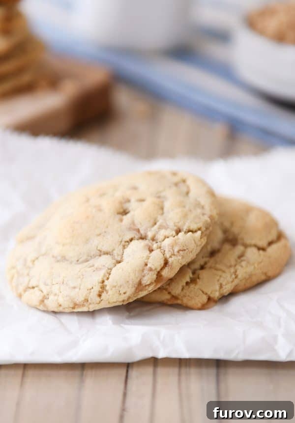Two perfectly baked thin toffee cookies resting on a piece of parchment paper, showcasing their delicate texture.