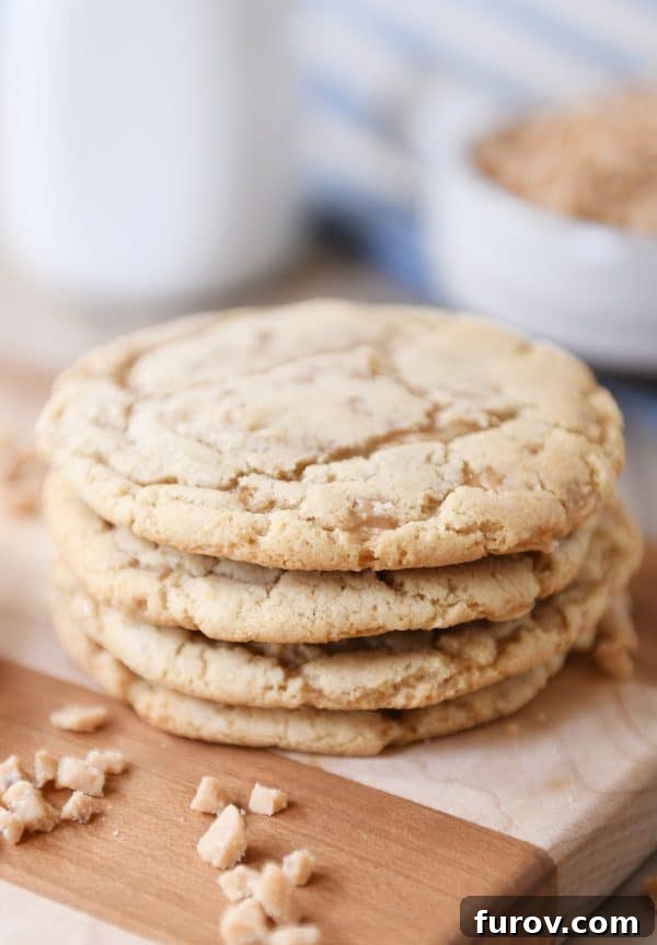 A stack of golden brown toffee cookies on a wooden cutting board, highlighting their inviting color and texture.