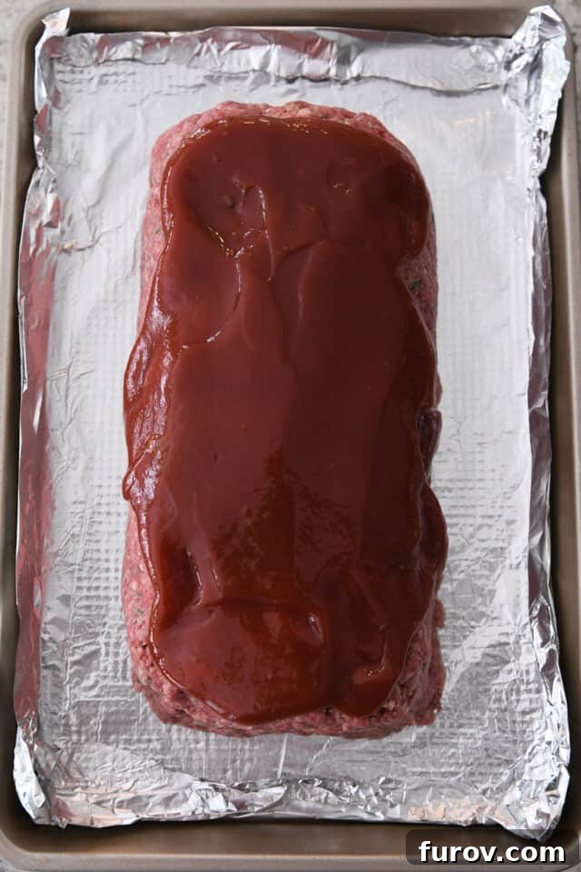 Sheet pan lined with foil with glazed meatloaf.