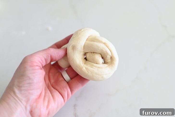 Simple Parmesan Garlic Knots 9 The crucial step of bringing the second end of the breadstick dough strip through the initial loop to form the classic knot shape.