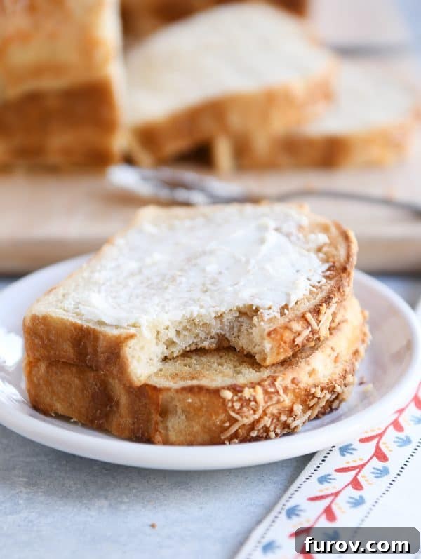 A slice of freshly baked bagel bread, spread generously with cream cheese, with a bite taken out.