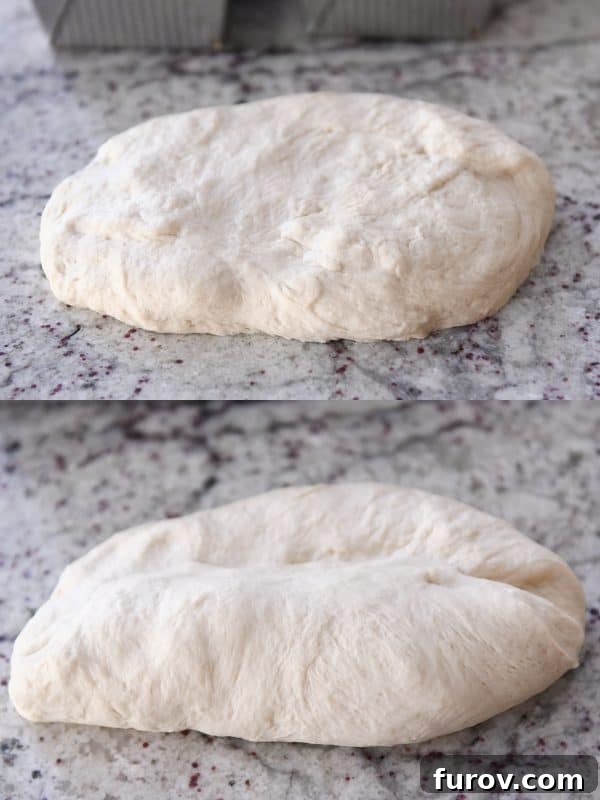 The initial stage of shaping raw bagel bread dough on a clean granite countertop, demonstrating the first crucial fold of the dough.