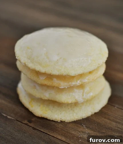 A stack of four light yellow buttermilk cookies on a countertop, glistening with a delightful glaze.
