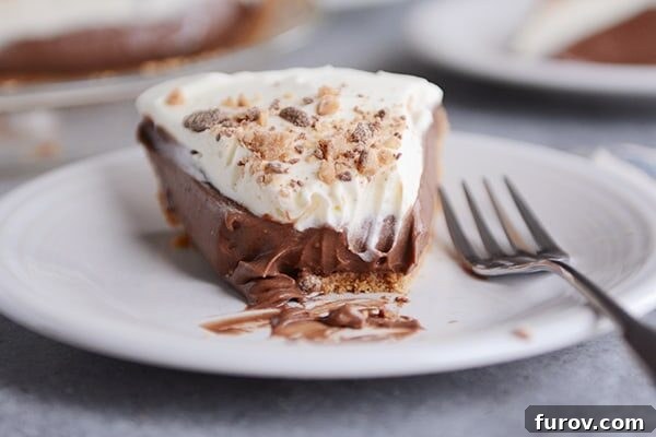 A generous slice of rich chocolate cream pie with a dollop of whipped cream, on a white plate ready to be served.