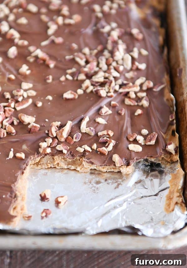 Effortless Peanut Butter Chocolate Graham Cracker Toffee 3 Sheet pan of easy graham cracker toffee with a few pieces taken out, showcasing the layers of caramel, peanut butter, and chocolate.