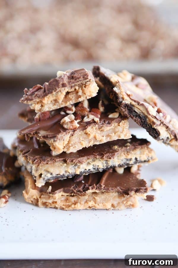 Effortless Peanut Butter Chocolate Graham Cracker Toffee 8 Close-up stack of easy graham cracker toffee with visible layers of graham cracker, caramel, peanut butter, and chocolate, topped with nuts.