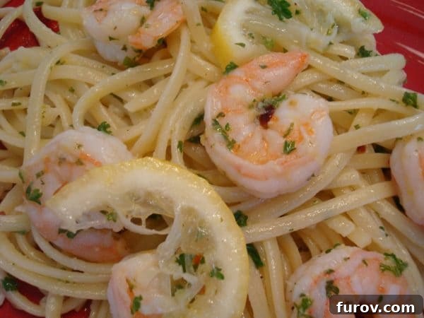 Sun Drenched Shrimp Scampi Linguine 2 A beautifully plated dish of golden linguine with plump pink shrimp, drizzled with rich scampi sauce and garnished with a fresh lemon slice.