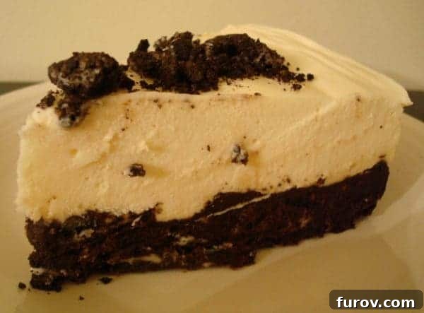 Decadent Oreo-Crusted White Chocolate Mousse Torte 2 A slice of elegant Oreo-Crusted White Chocolate Mousse Torte on a white plate, showcasing its creamy filling and dark crust.