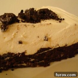 A whole Oreo-Crusted White Chocolate Mousse Torte, garnished with cookie crumbles, ready to be served.