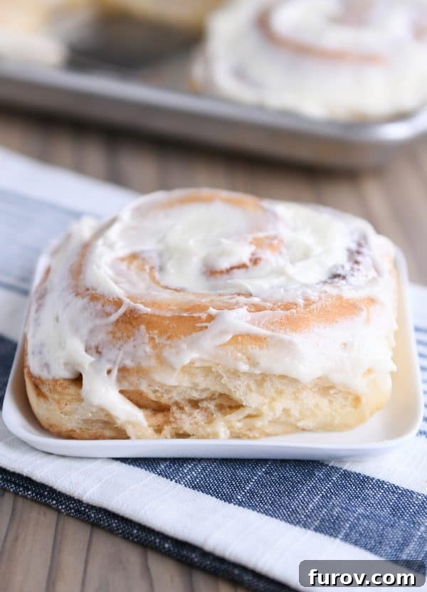 Master Cheryl's Famous Cinnamon Rolls: A Step-by-Step Guide to the Best Recipe and Baking Secrets 2 A perfectly frosted cinnamon roll on a pristine white square plate, showcasing its soft texture and generous icing.