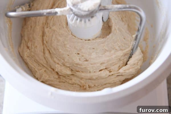 Master Cheryl's Famous Cinnamon Rolls: A Step-by-Step Guide to the Best Recipe and Baking Secrets 11 Cinnamon roll dough mixing in a Bosch stand mixer, with the sides scraped down, showing a more uniform, though still wet, consistency.