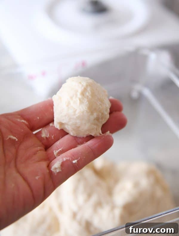 Master Cheryl's Famous Cinnamon Rolls: A Step-by-Step Guide to the Best Recipe and Baking Secrets 17 A baker's hand rolling a small portion of the sticky cinnamon roll dough into a ball to test its consistency.