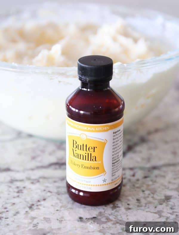 Master Cheryl's Famous Cinnamon Rolls: A Step-by-Step Guide to the Best Recipe and Baking Secrets 28 A bottle of butter vanilla emulsion positioned in front of a bowl of creamy, white cinnamon roll frosting.