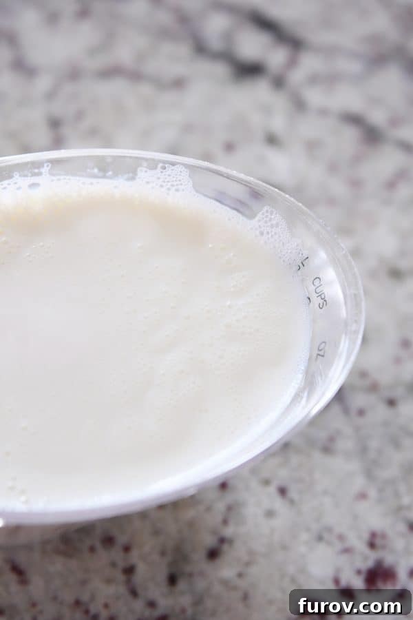 Master Cheryl's Famous Cinnamon Rolls: A Step-by-Step Guide to the Best Recipe and Baking Secrets 7 A liquid measuring cup holding scalded milk, showing steam rising and small bubbles around the edges.