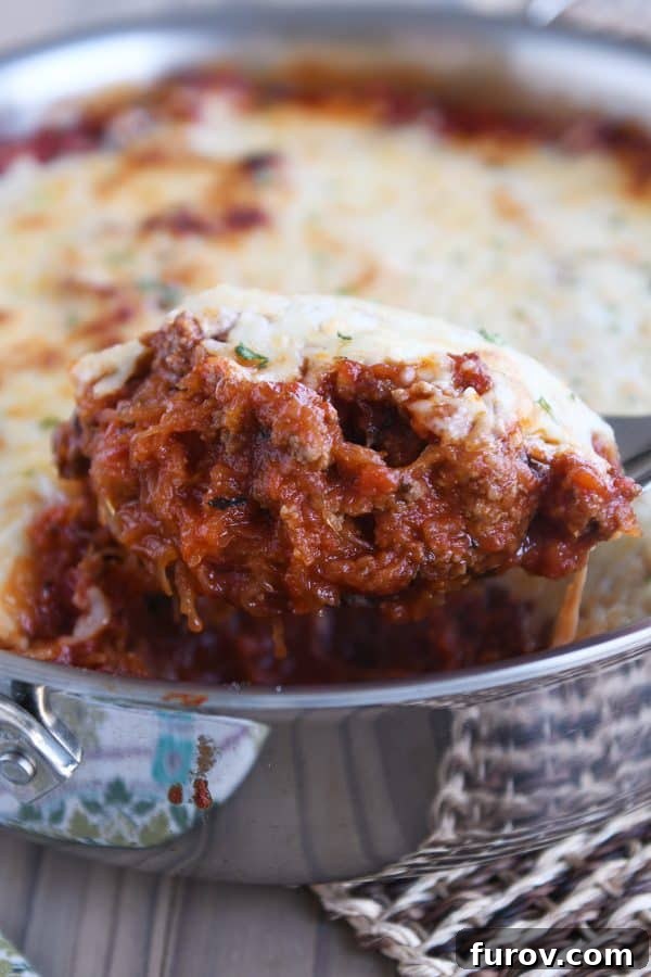 Scoop of Spaghetti squash spaghetti bake topped with cheese in pan.