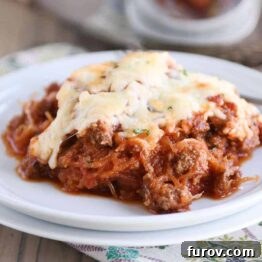 Scoop of Spaghetti squash spaghetti bake topped with cheese on a white plate.