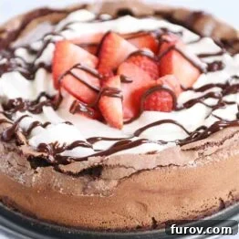 Fallen chocolate cake with whipped cream, strawberries, and chocolate drizzle, beautifully presented.