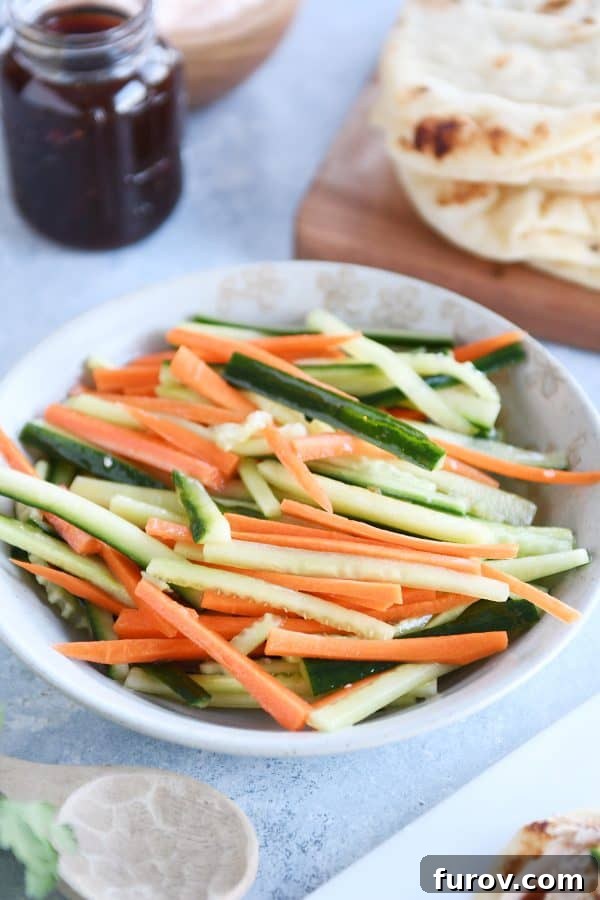 Fast Chicken Banh Mi Flatbread with Two Amazing Sauces 5 Tan bowl filled with vibrant pickled cucumber and carrot sticks, ready to add a tangy crunch.