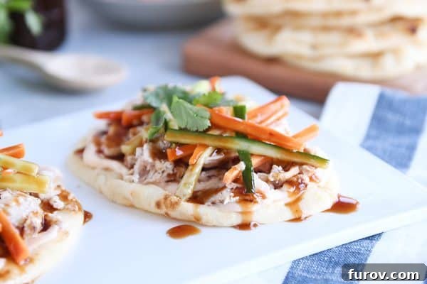 Fast Chicken Banh Mi Flatbread with Two Amazing Sauces 6 Chicken banh mi flatbread with pickled cucumbers and carrots on white platter, showcasing a fully assembled meal.
