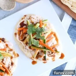 Top down view of Chicken banh mi flatbread with pickled cucumbers and carrots on white platter.