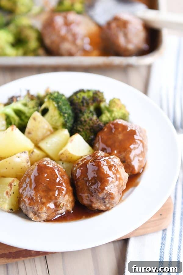 One-Pan Sweet & Sour Meatballs, Roasted Potatoes & Broccoli 2 A white plate generously filled with glistening sweet and sour meatballs, drizzled with rich sauce, and surrounded by perfectly roasted potatoes and vibrant green broccoli florets, ready to be enjoyed.