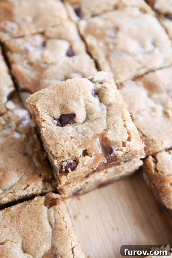 Salted Caramel Brown Butter Chocolate Chip Bars 2 Slab of salted caramel brown butter chocolate chip bars cut into squares and two stacked on each other on wood cutting board.