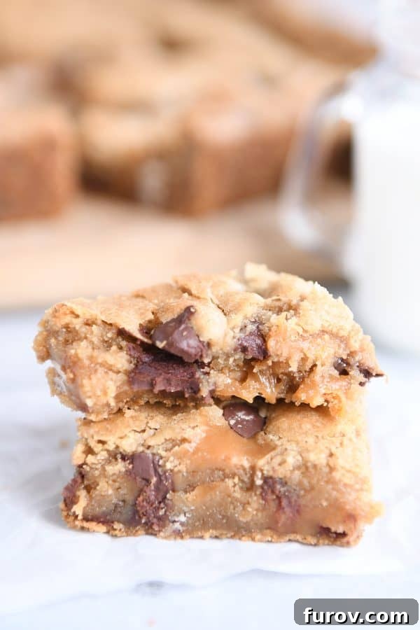 Salted Caramel Brown Butter Chocolate Chip Bars 3 Two salted caramel brown butter chocolate chip bars stacked on each other on white wax paper.