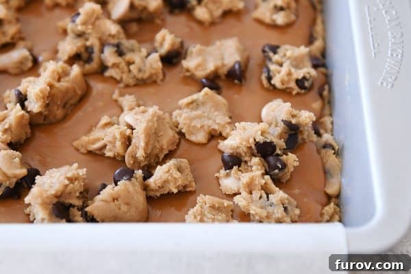 Salted Caramel Brown Butter Chocolate Chip Bars 6 Process shot of chocolate chip cookie dough dotting surface of caramel.