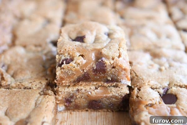 Salted Caramel Brown Butter Chocolate Chip Bars 8 Slab of salted caramel brown butter chocolate chip bars cut into squares and two stacked on each other on wood cutting board.